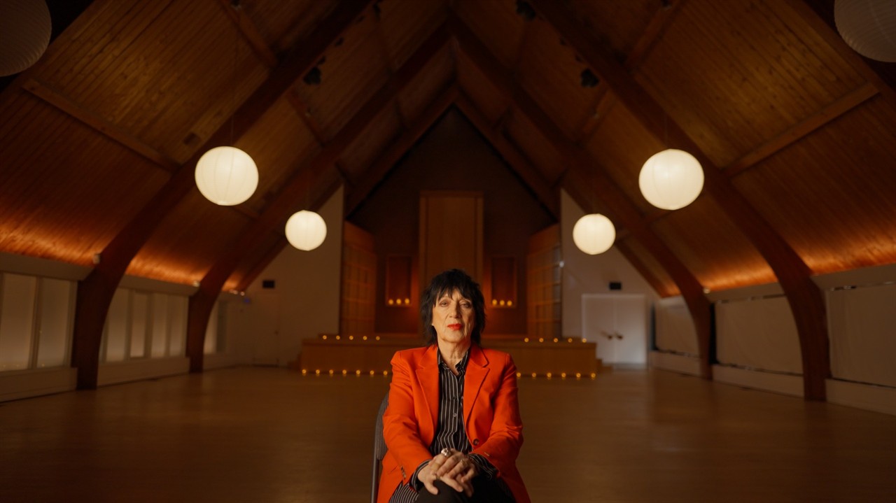 Carol Pope sitting in a large, long room